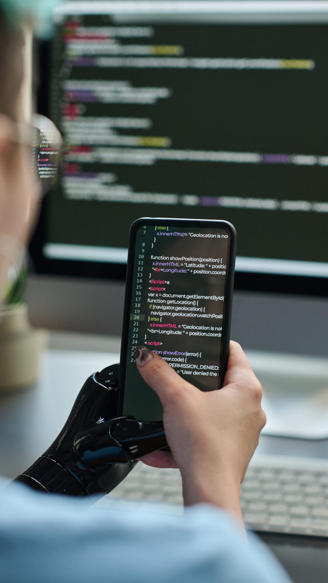 Vertical image of girl with prosthetic hand typing program codes on smartphone